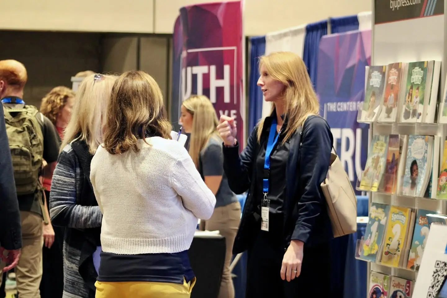 Attendees talking with a curriculum vendor among the display tables in the exhibit hall.