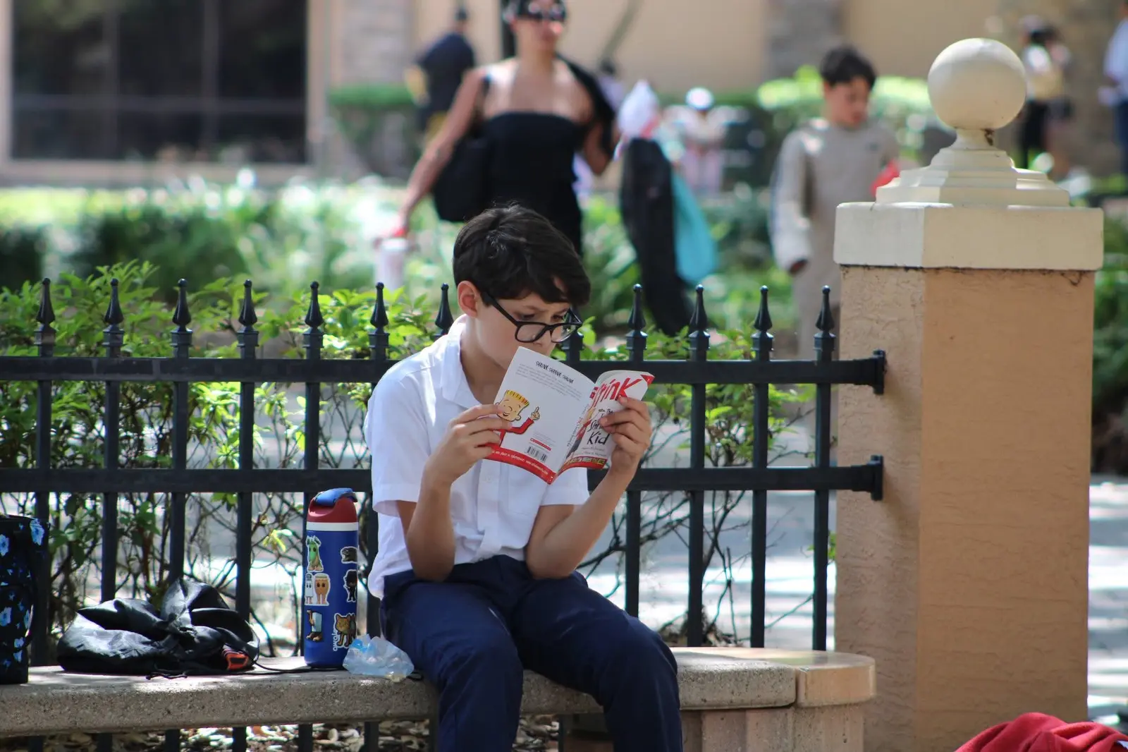 A student sitting on a low wall outside, reading through sheet music before competing.