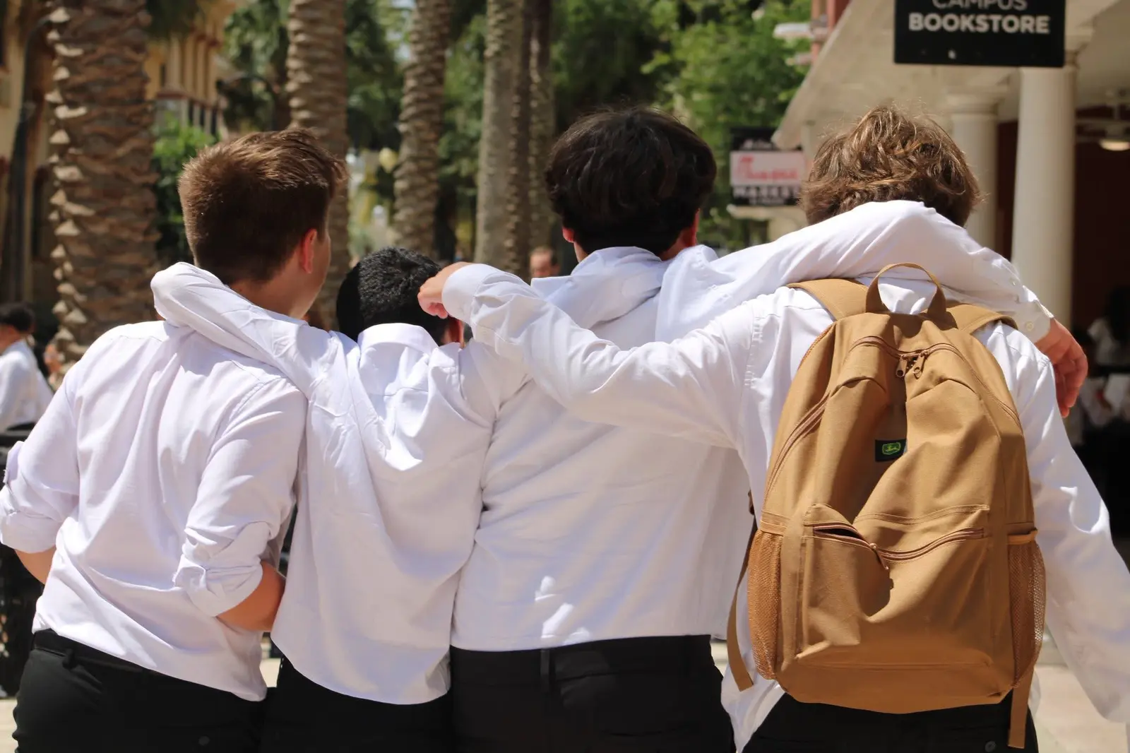 Students in white shirts walking together with their arms around each other's shoulders after a competition.